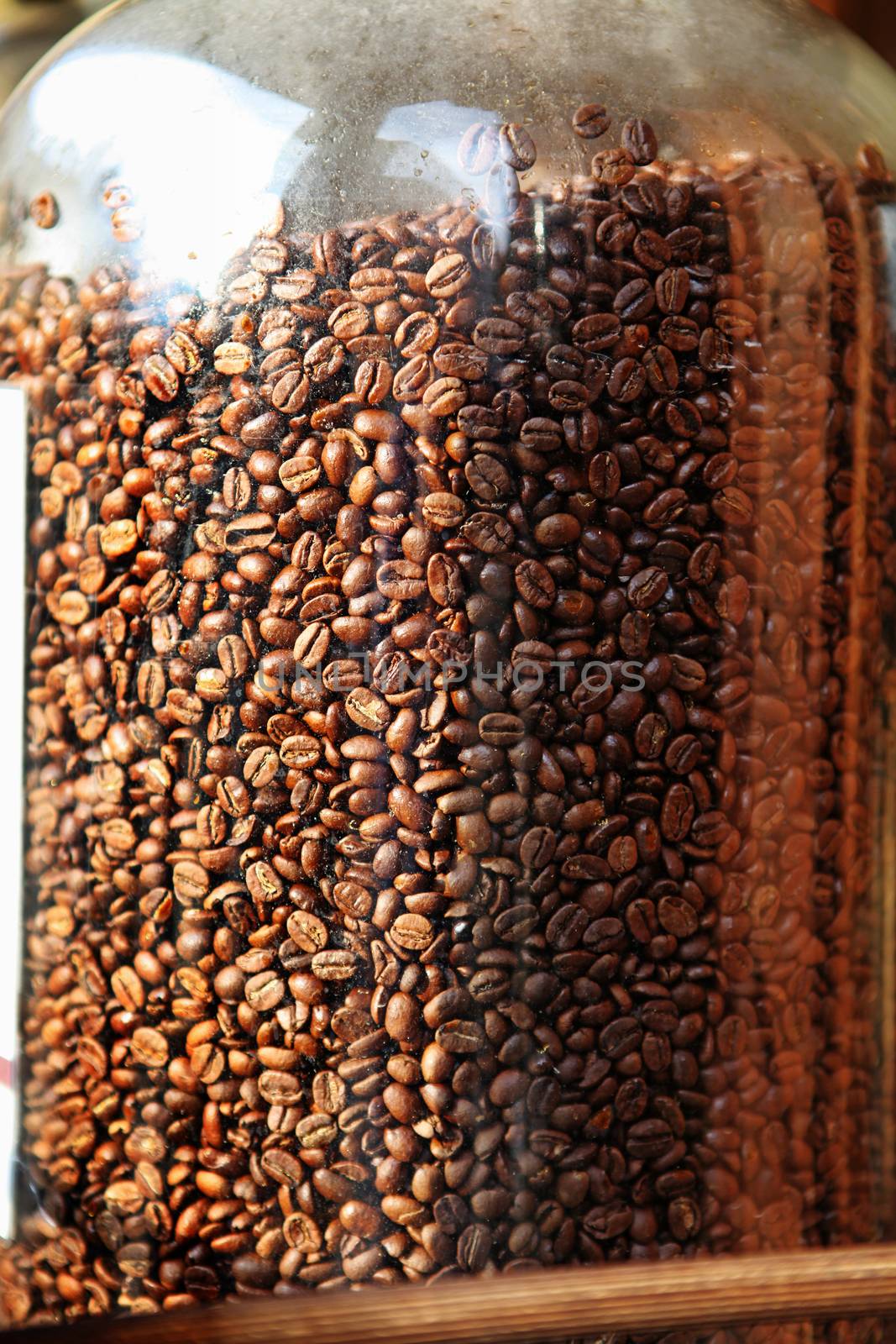 Brown coffee beans in glass container, close-up of coffee beans for background and texture