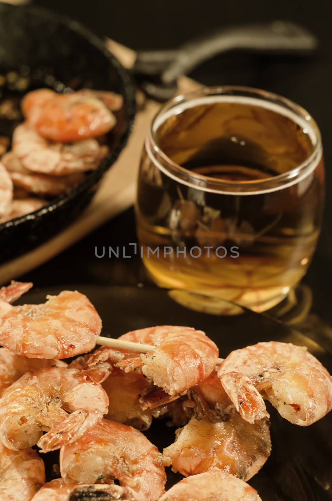 Dish of fried shrimp on a skewer and beer in the glass. Selective focus, toned brown.