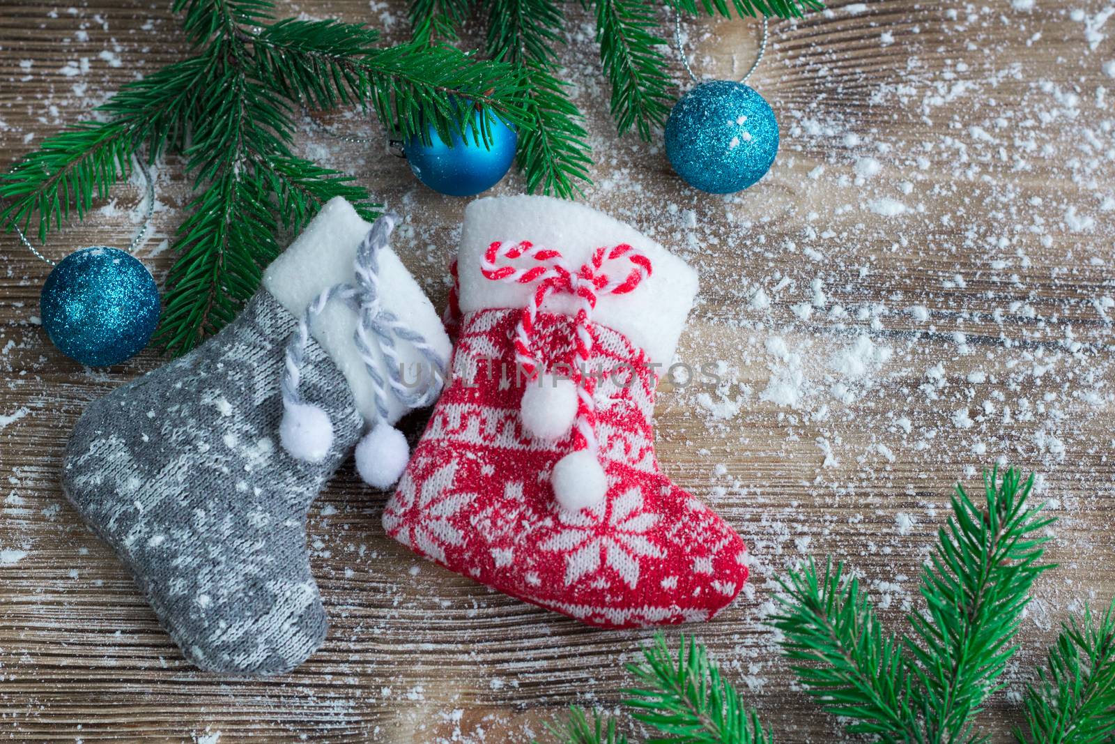Christmas and New Year winter holiday snowbound composition of stockings on wooden space background with green fir tree branches and balls ornament