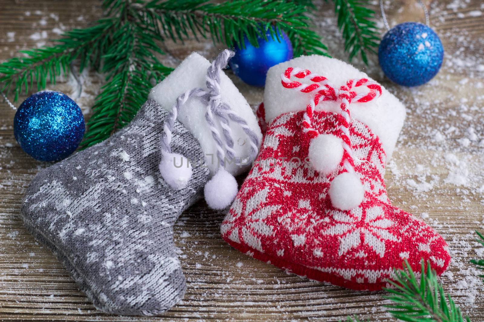 Christmas and New Year winter holiday snowbound composition of stockings on wooden space background with green fir tree branches and balls ornament