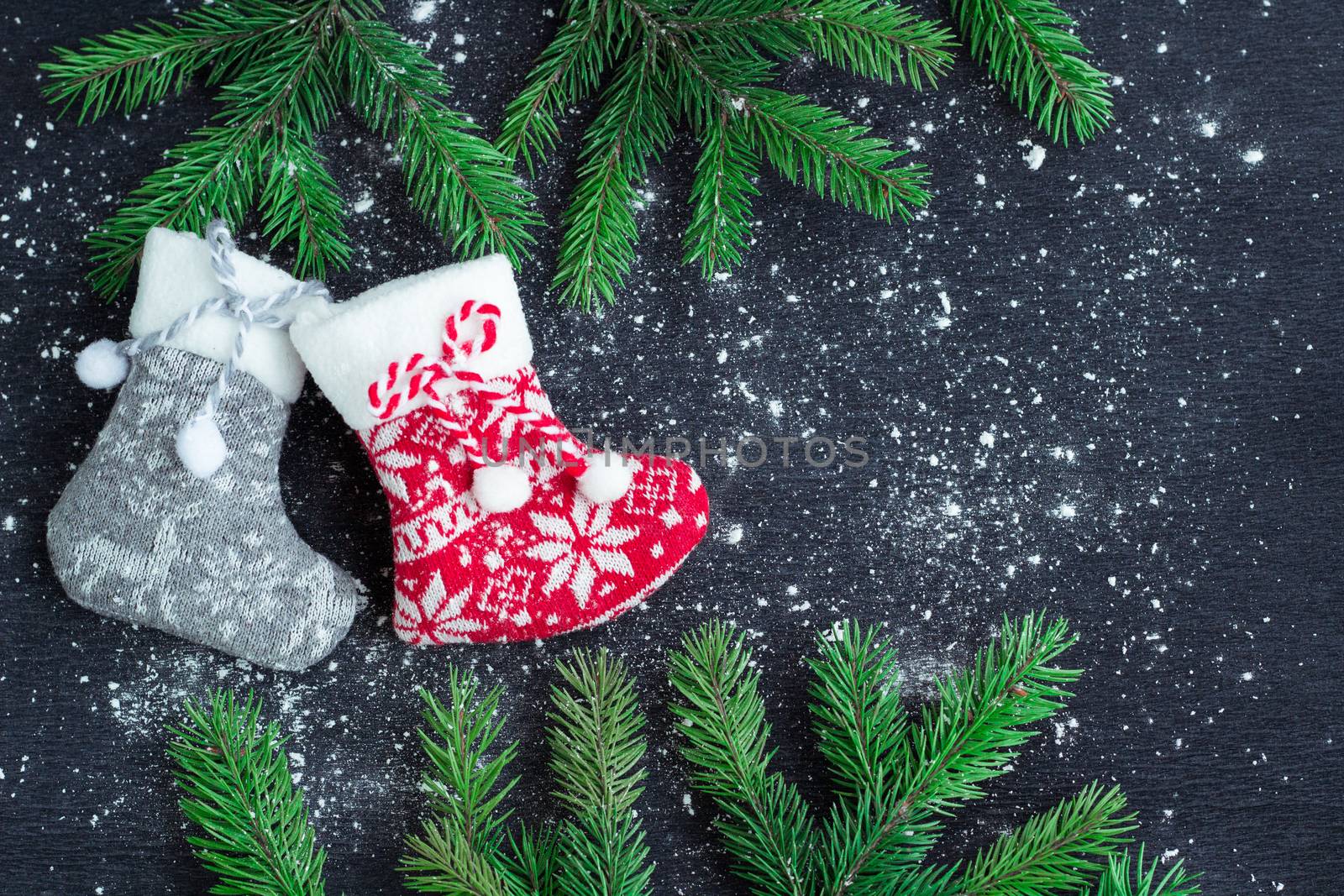 Christmas and New Year winter holiday snowbound composition of grey and red stockings on black space background with green fir tree branches