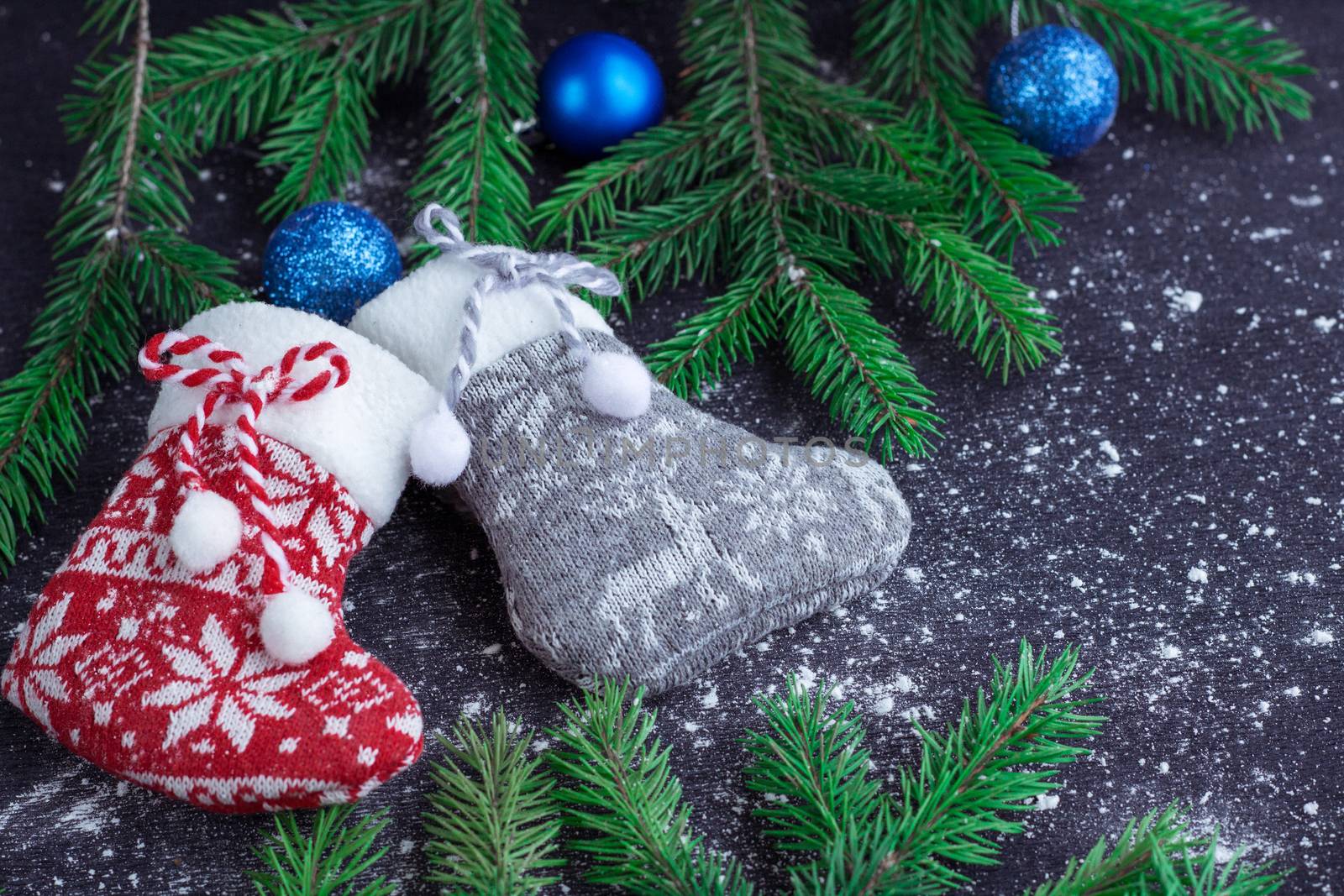 Christmas and New Year winter holiday snowbound composition of red and grey stockings on black space background with green fir tree branches and blue balls ornament