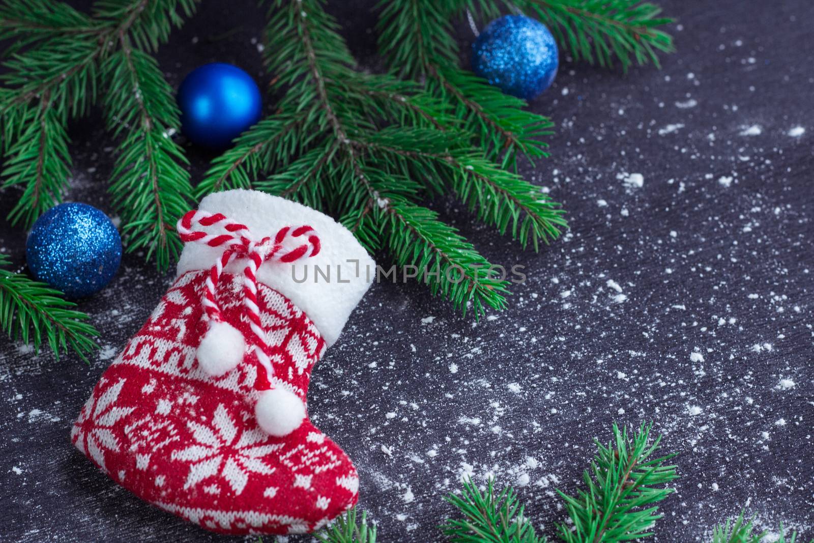 Christmas and New Year winter holiday snowbound composition of red stocking on black space background with green fir tree branches and blue balls ornament