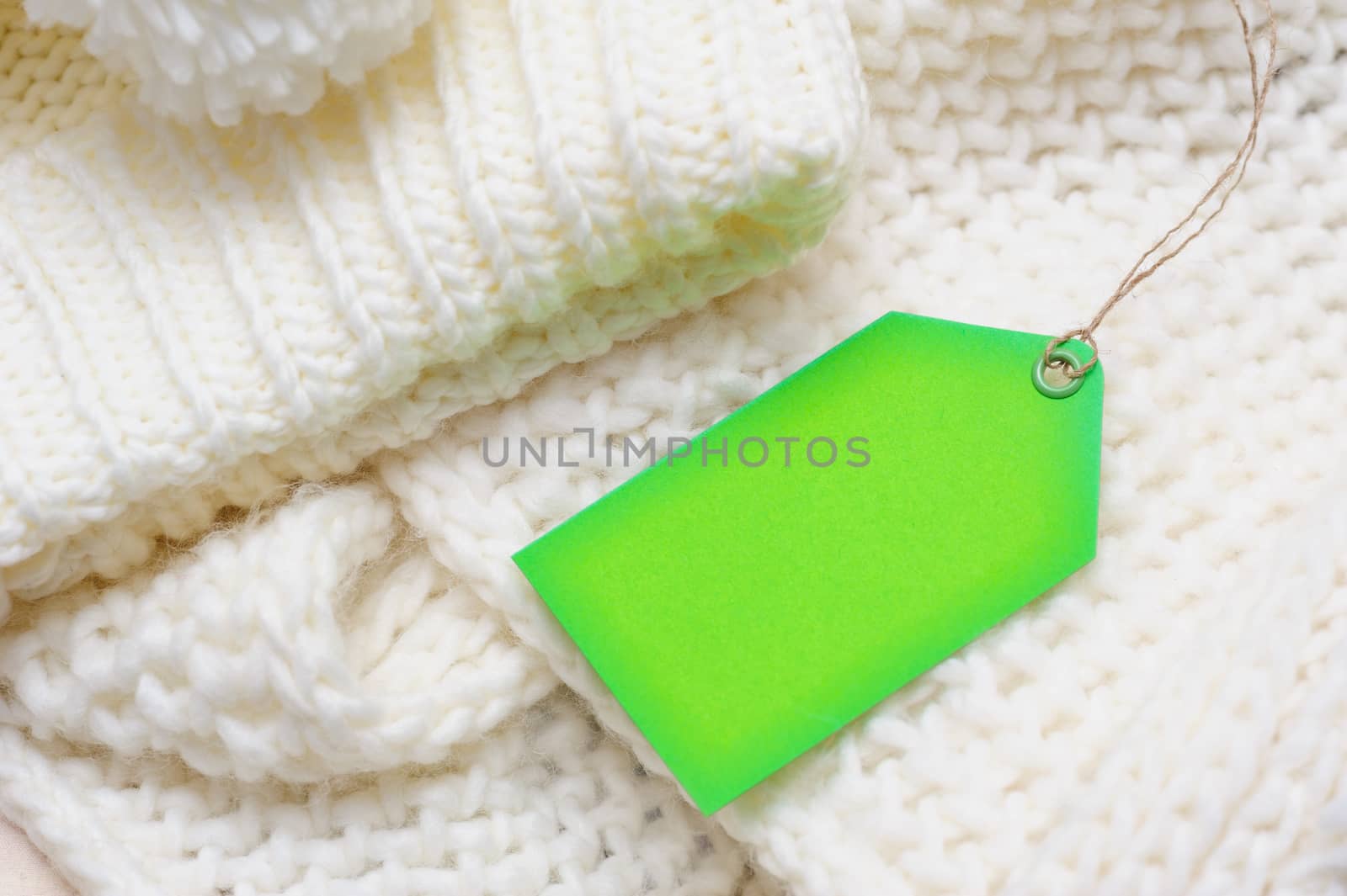 white texture knitted scarf and hat with a green tag.