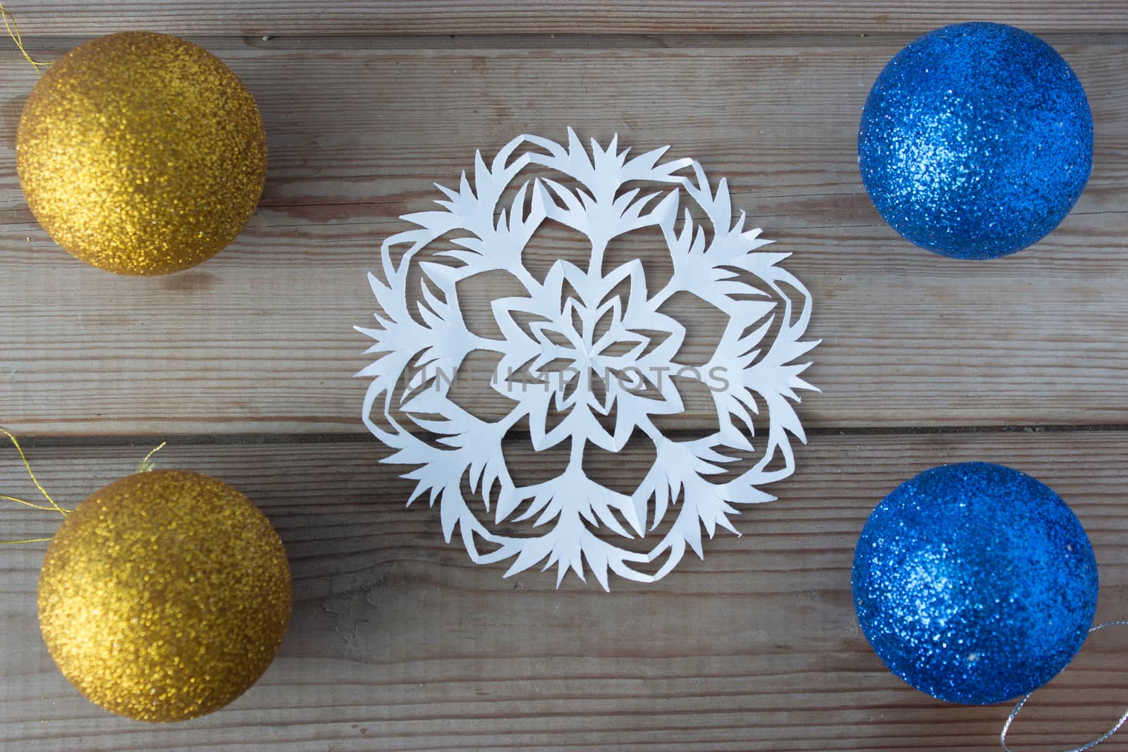 paper snowflake and Christmas balls on the wooden table