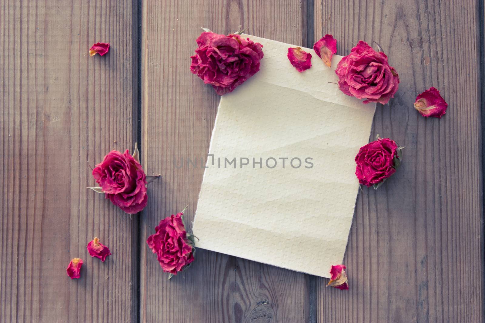 note and dry pink roses on wooden table