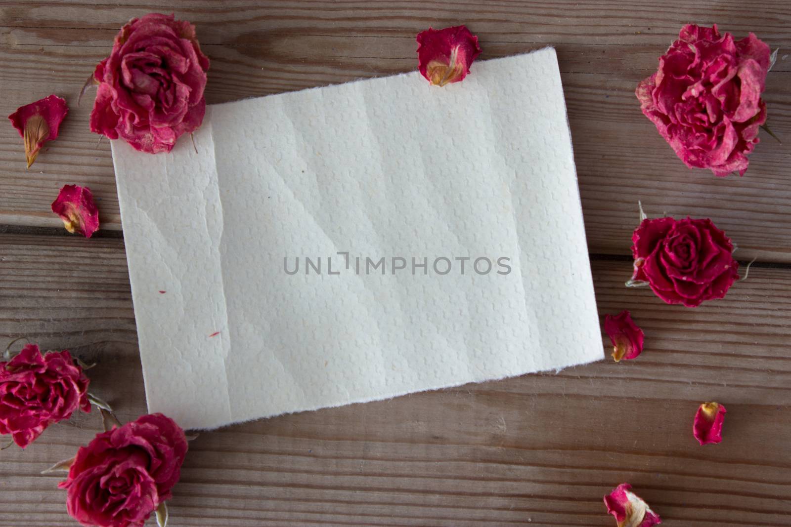 note and dry pink roses on wooden table