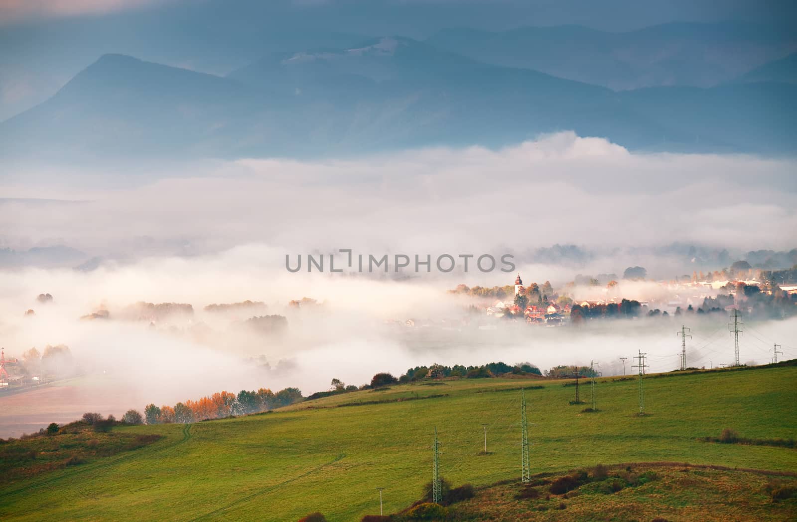 Foggy sunny morning in mountain village. Misty hills in Slovakia Tatras mountains. 