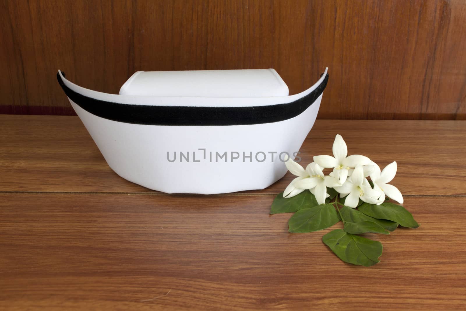 Hat nurse white and Millingtonia hortensis flowers on wood table. symbol of nursing thailand and Thai traditional medicine.