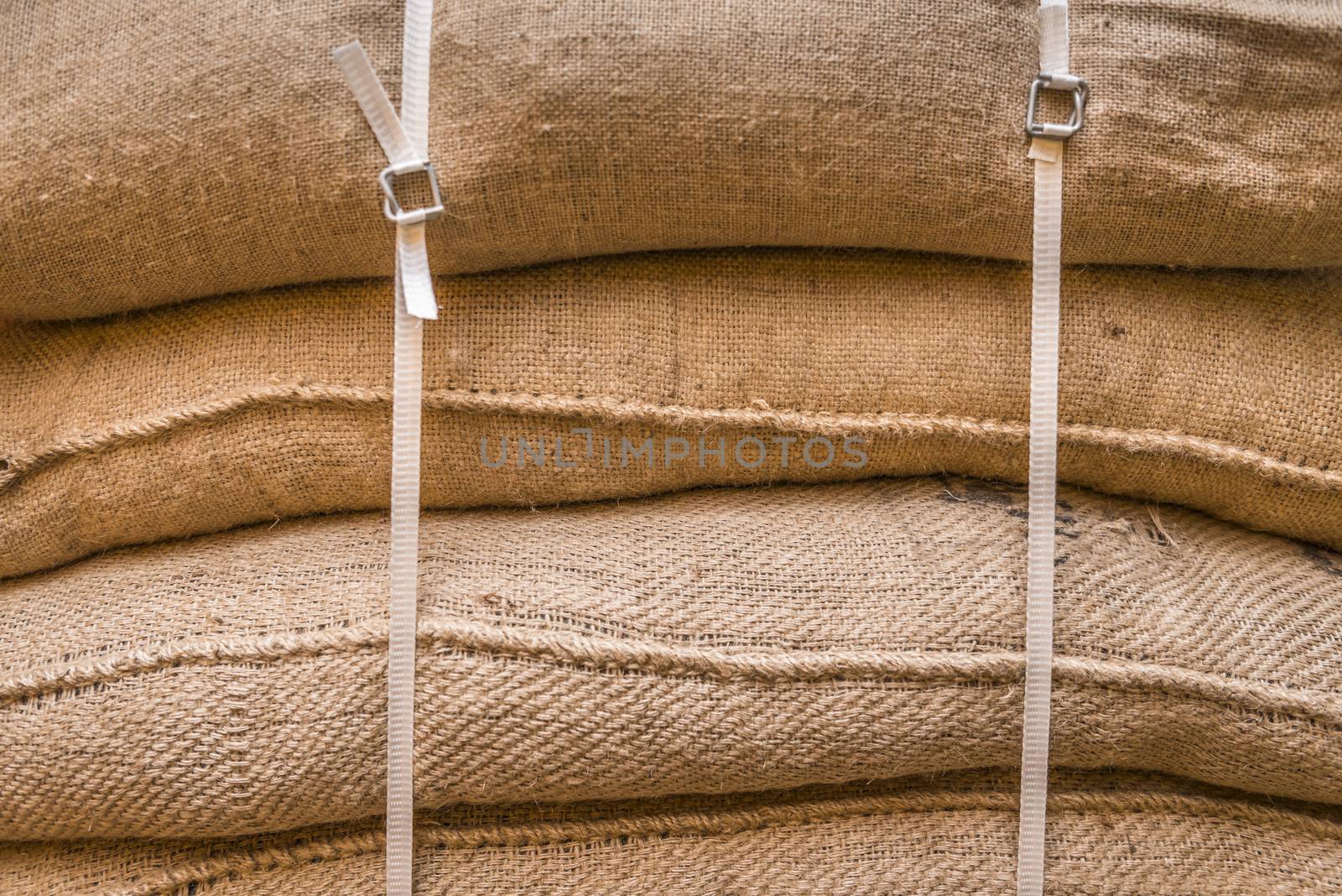 Close-up image of jute sacks filled with goods, piled upon each other and tied up, ready for transportation.