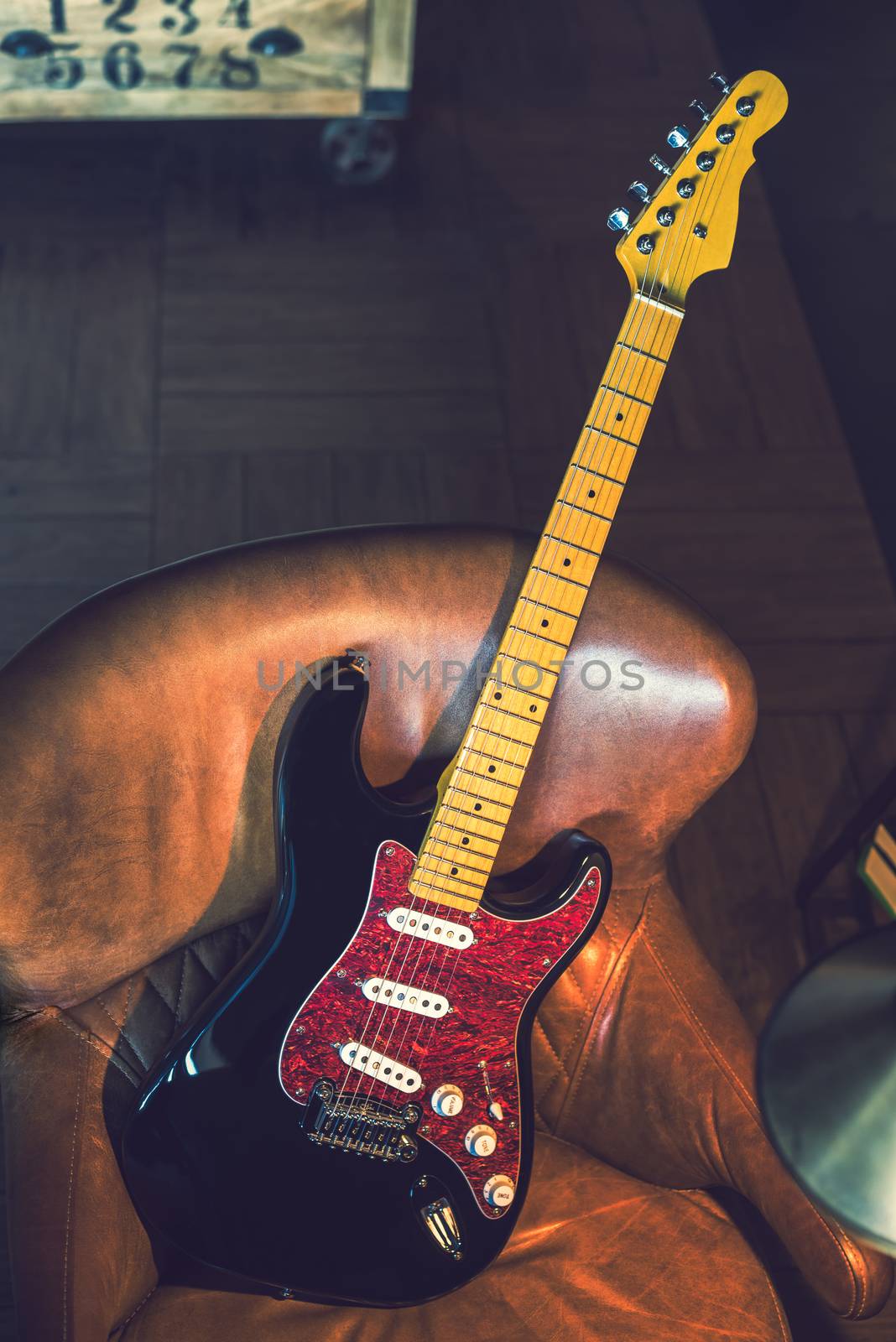 Electric Guitar Leaning Against a Couch. Electric Guitar. Black and Red Finish. Stiil life with Electric Guitar.