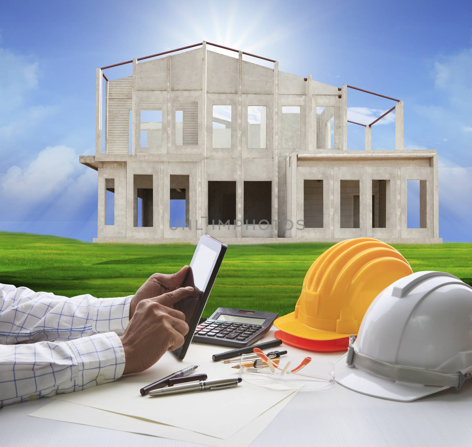 hand of architect working on computer tablet  and house construction background