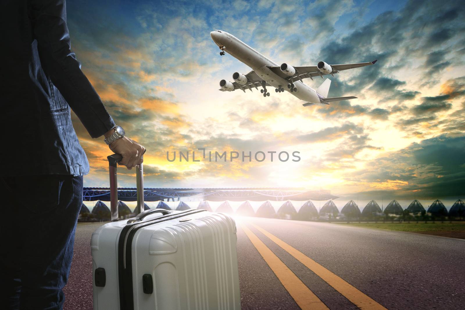 business man and traveling luggage standing in airport terminal and passenger plane flying over sky