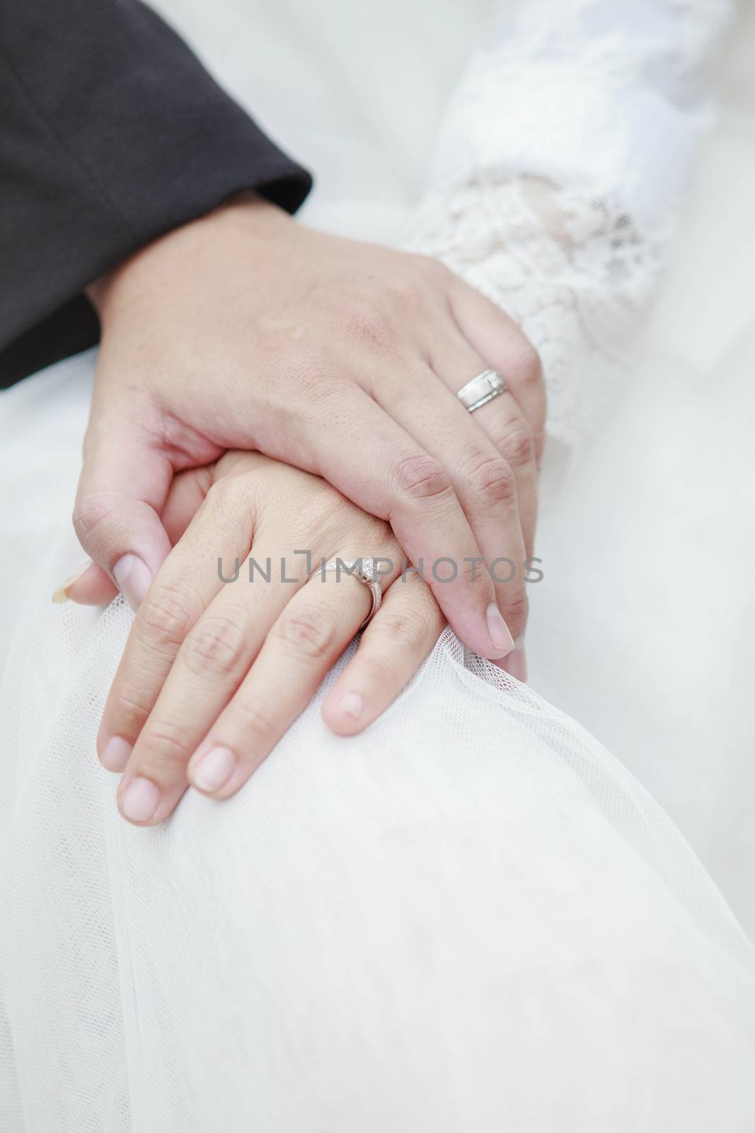 hand of groom and bride warming holding with wedding daimond ring 