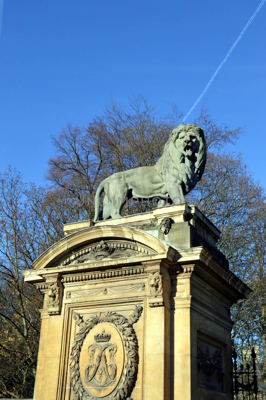 A sculptured lion on a pillar in front of a portico