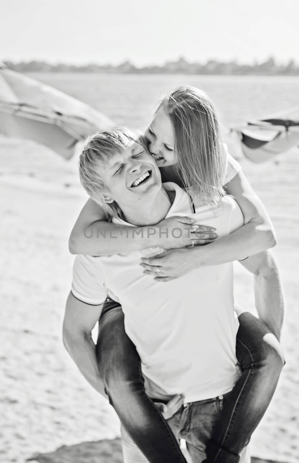 Young couple in love having fun and jumping on the beach by natazhekova