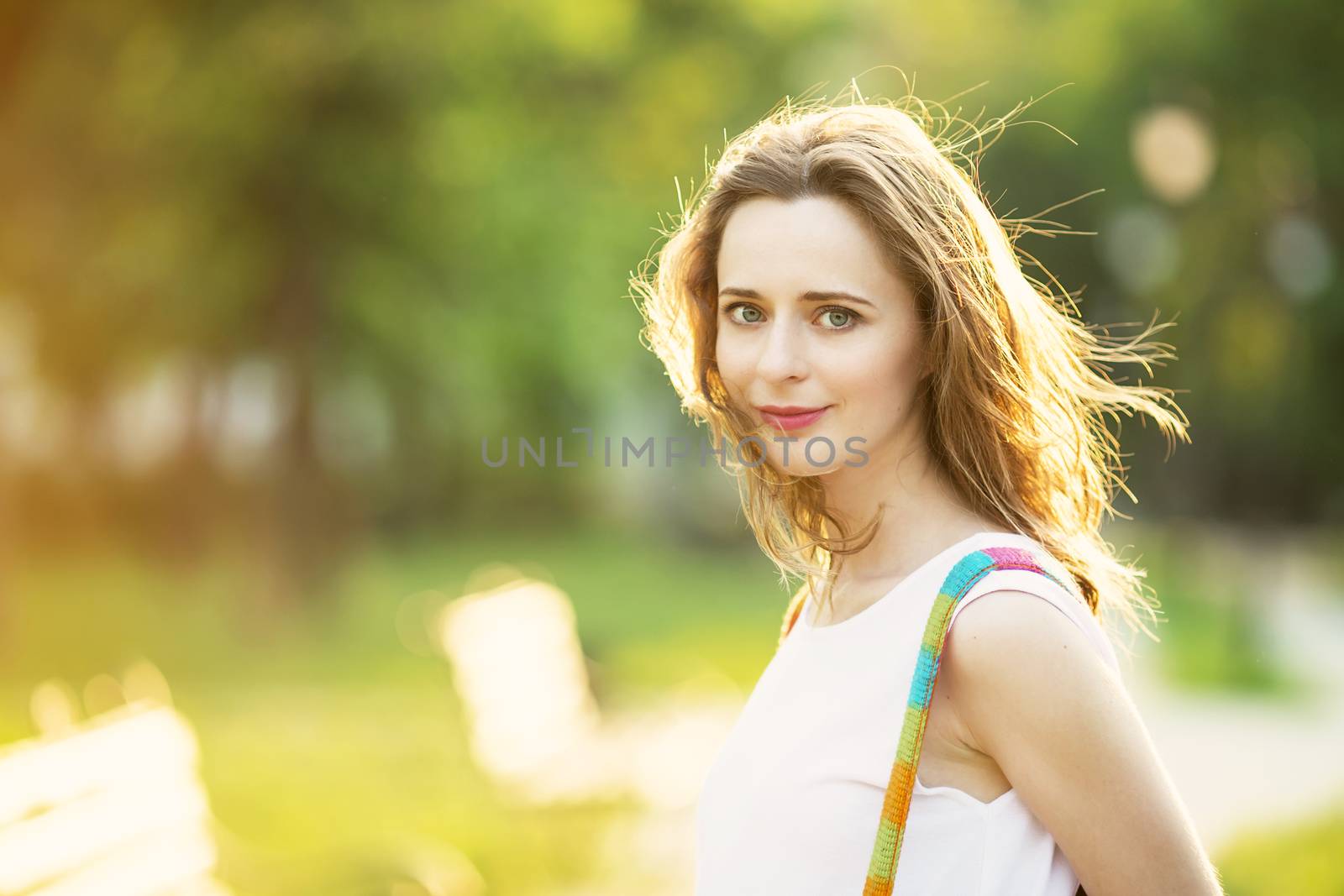 Portrait of lovely urban girl with backpack in the street. Happy smiling woman. Fashionable blonde girl walking in a city park