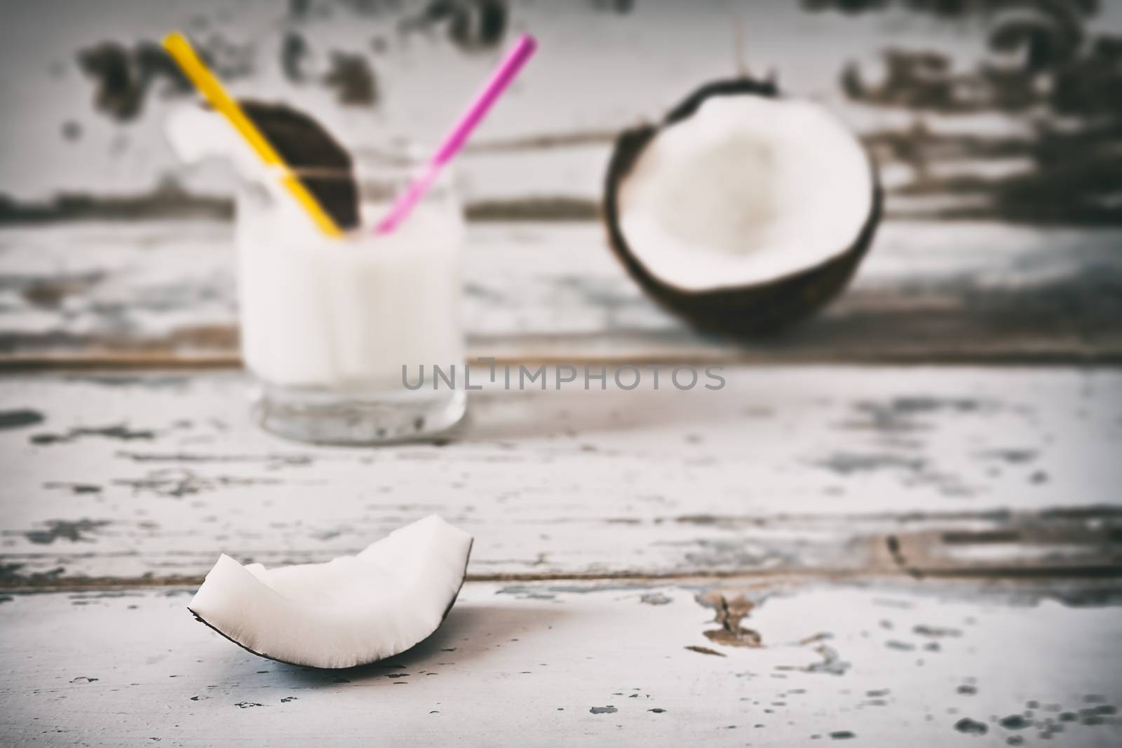 Slice of coconut over an old table and coconut milk on background