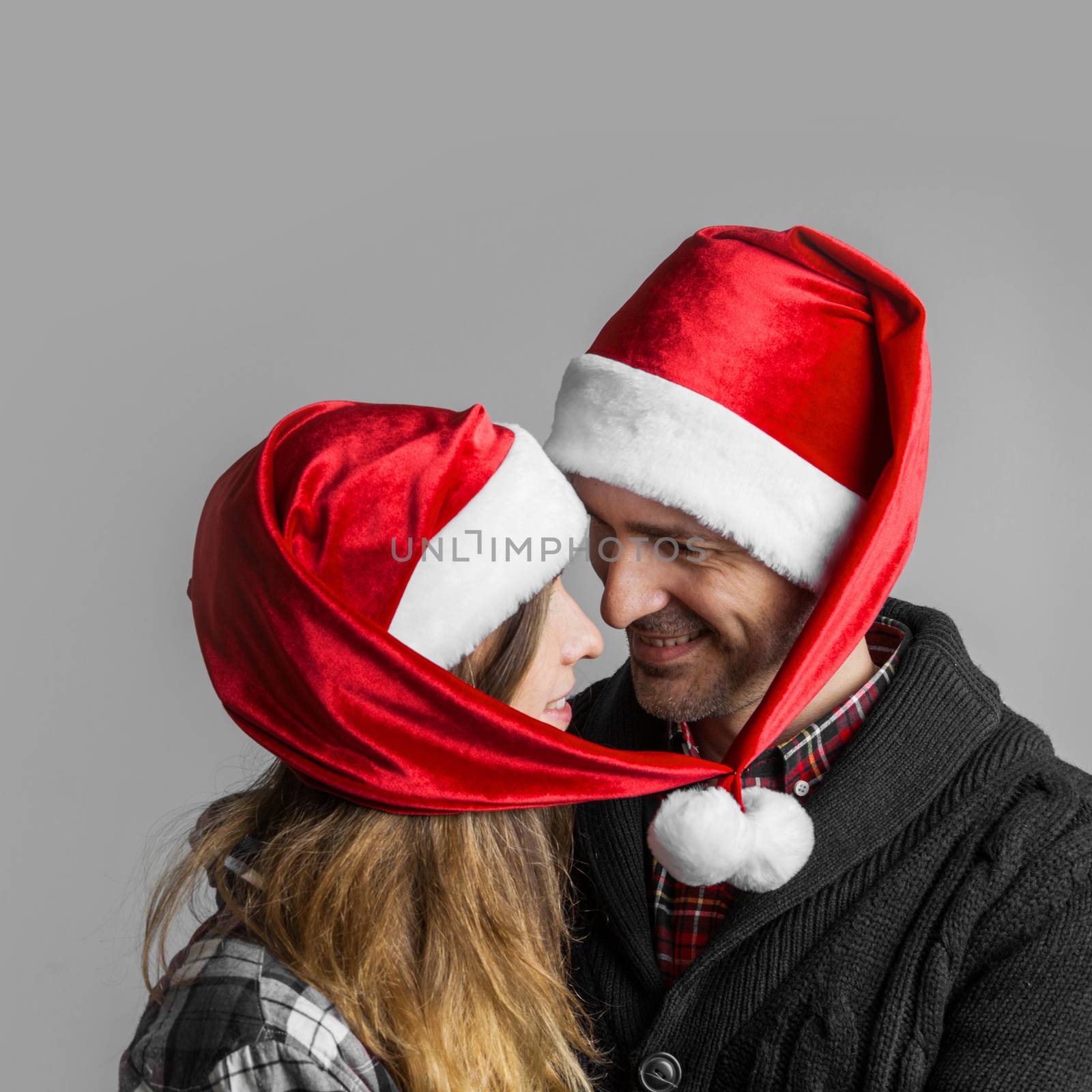 Happy smiling couple in Santa's hats bound together