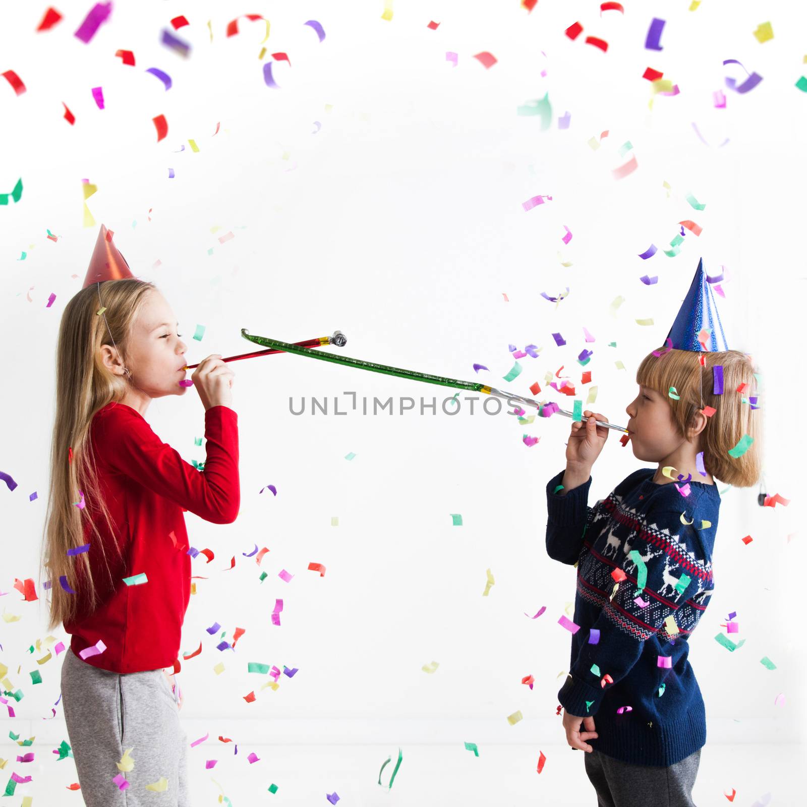 Children blowing party trumpets with confetti celebrating new year