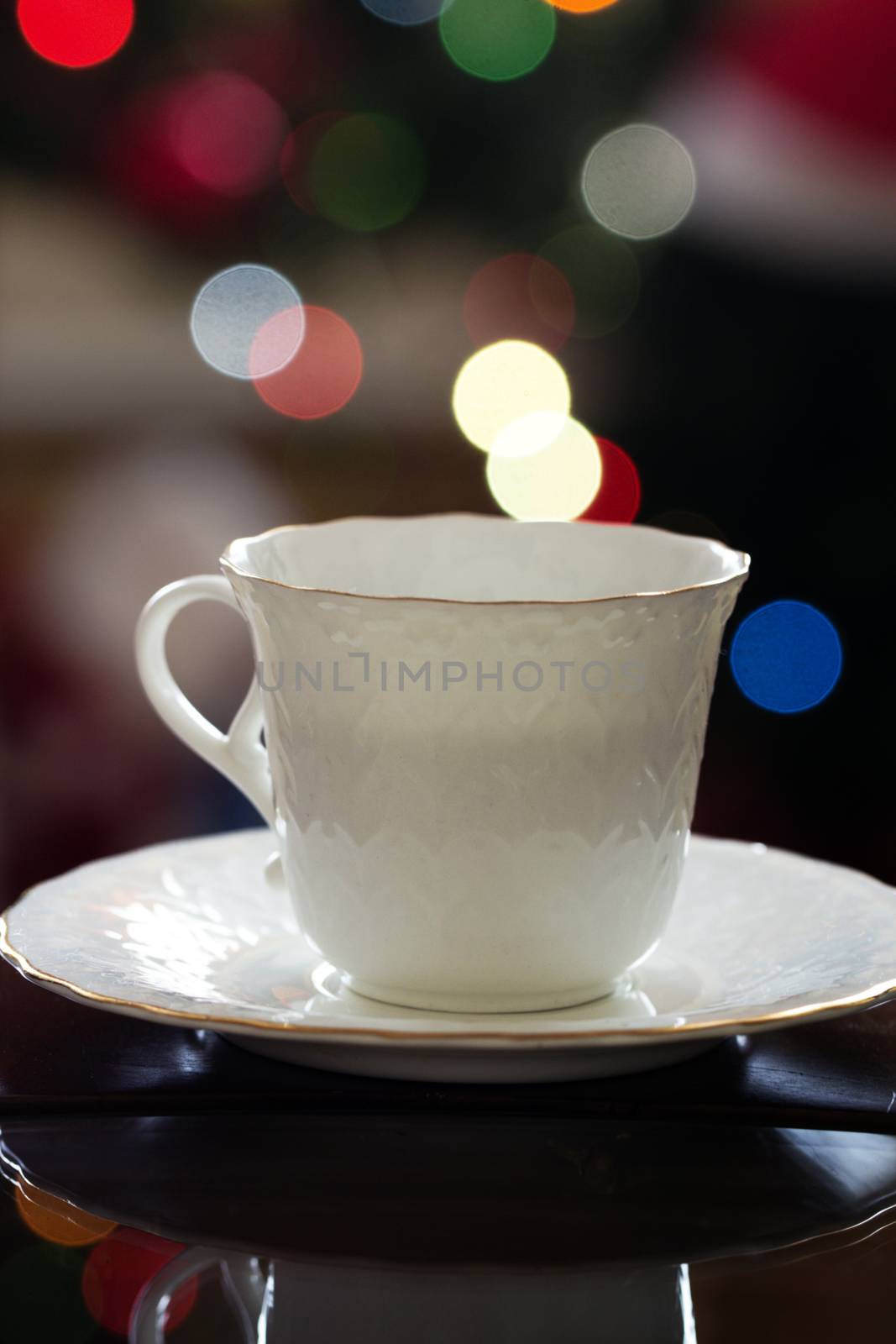  cup of hot tea or coffee and christmas tree with lights in background. Cup of coffee  on a Christmas light background.