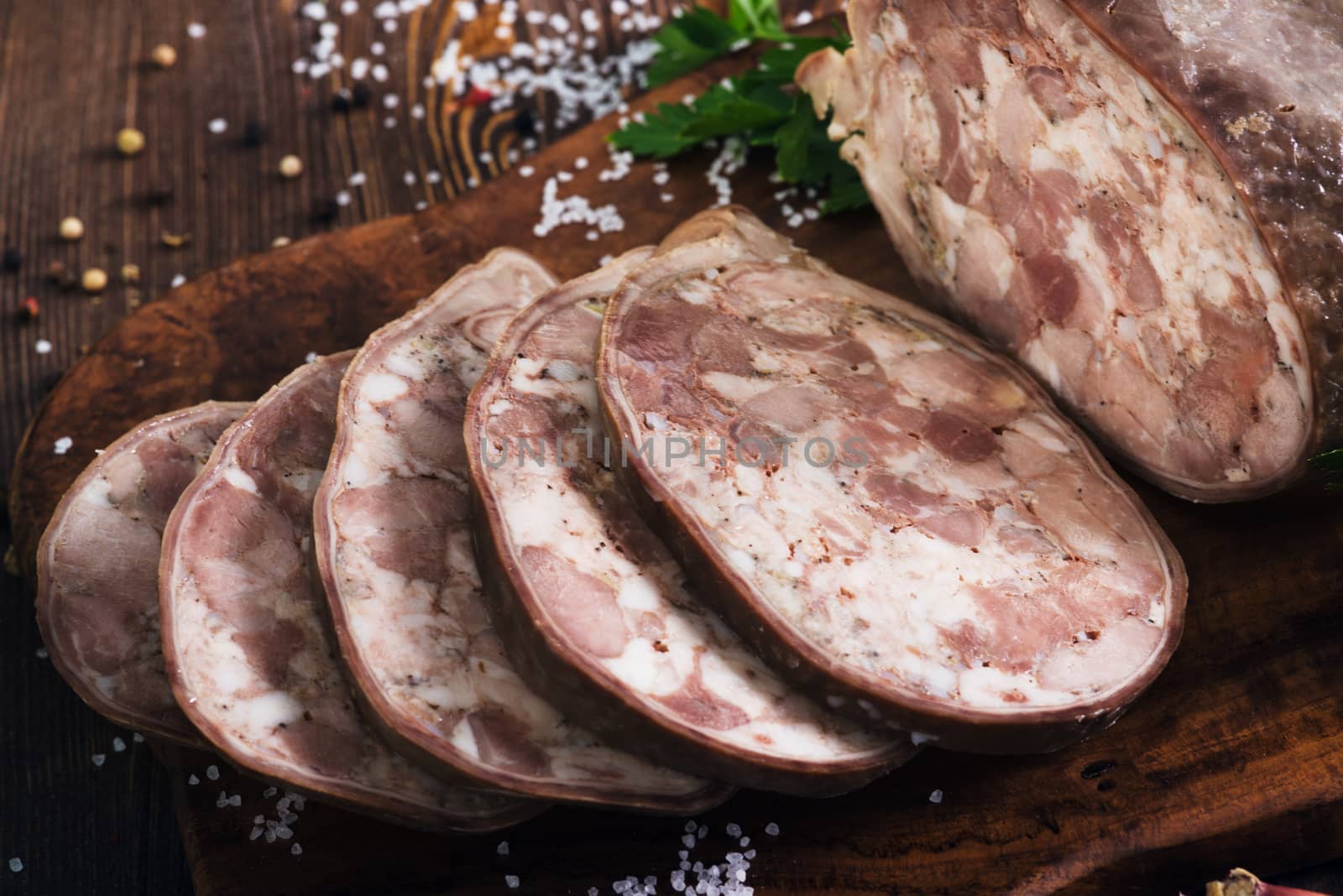 Sliced pork saltisons with herbs on a slate cutting board on wooden background