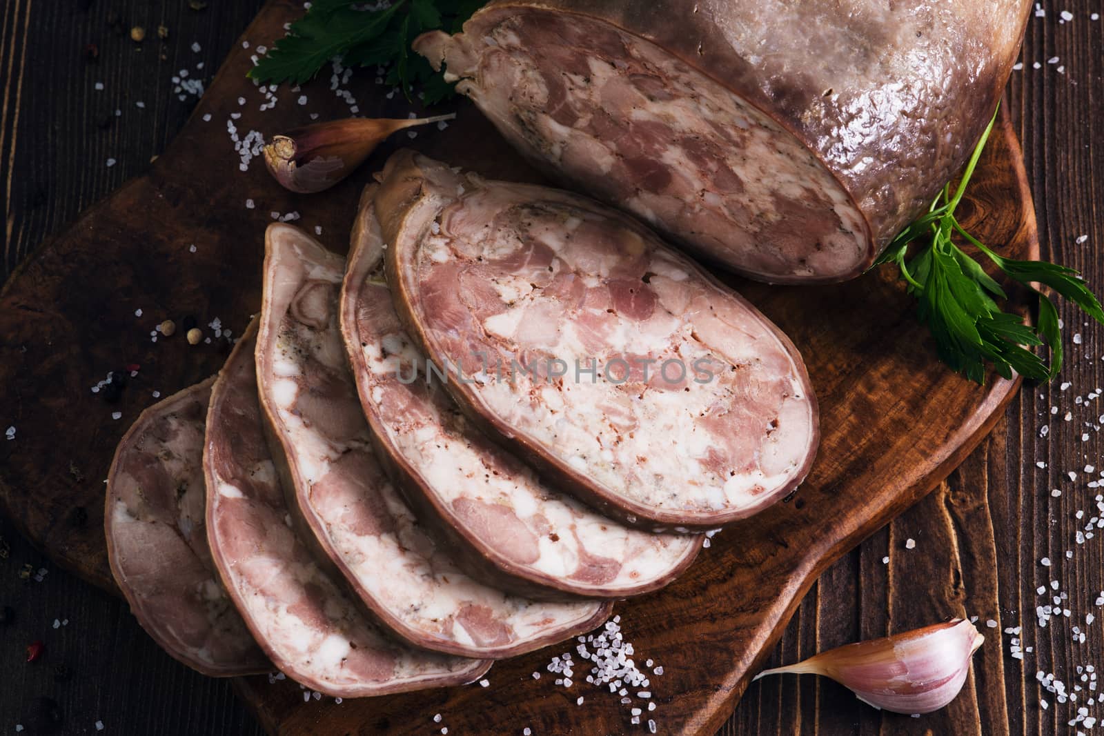 Sliced pork saltisons with herbs on a slate cutting board on wooden background