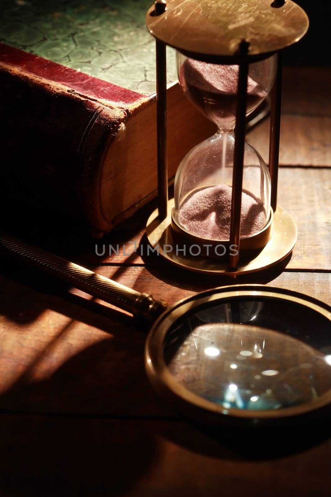 Vintage still life. Magnifying glass and hourglass near old book