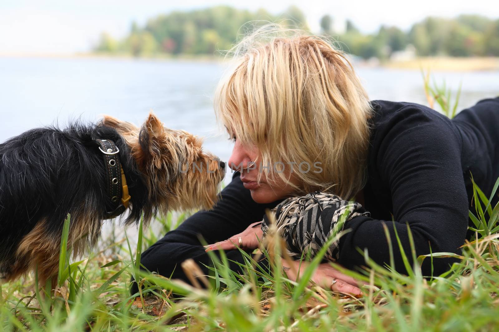 Woman and small dog portrait on lake shore background. Autumn, lake, nature, tenderness