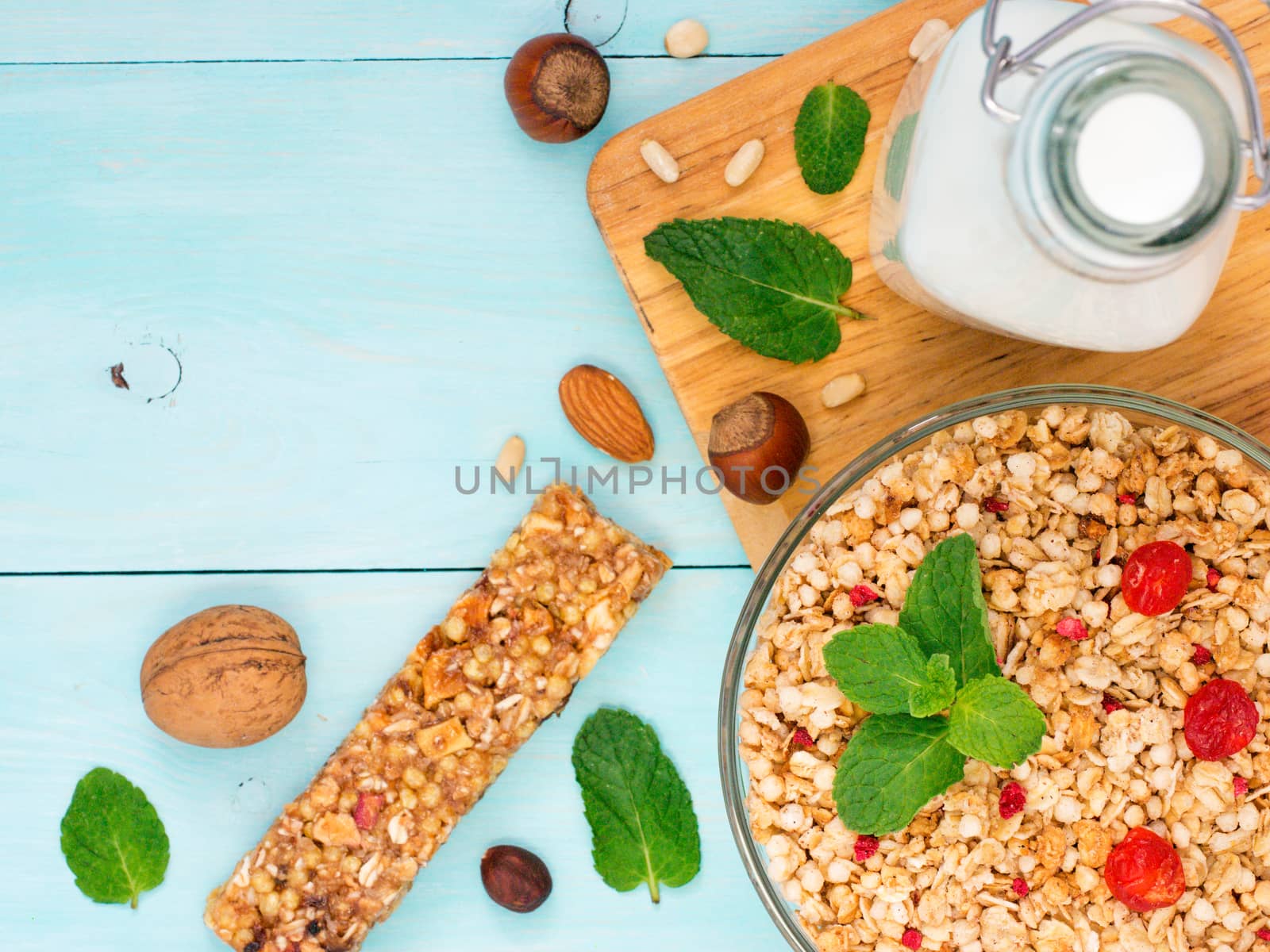 Colorful health breakfast concept. Muesli, milk, granola bar nuts on blue wooden background. Top view or flat lay. Copy space