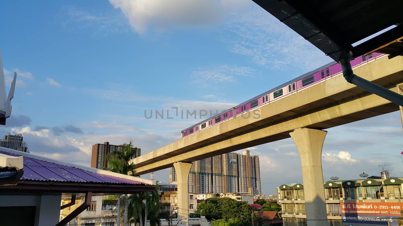 Bangkok, Thailand - November 12, 2016: The purple line sky train is moving on the track. The photo show the under construction resident building and the local home-fitting store.