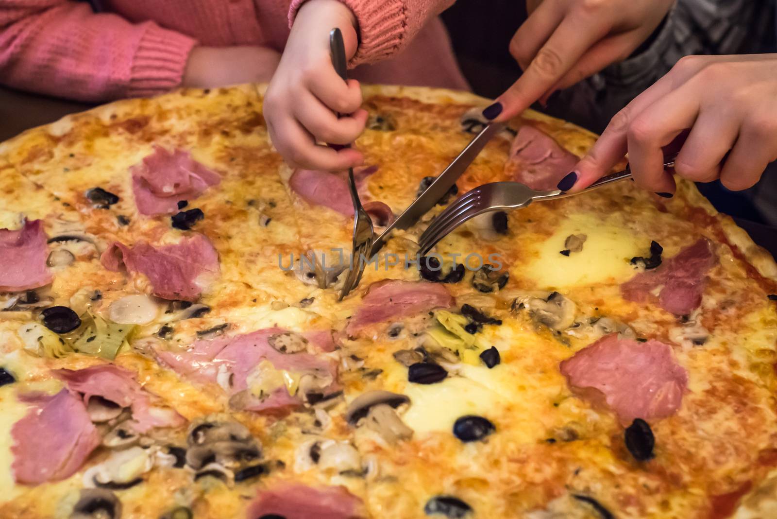 children hands cut pizza on wooden board