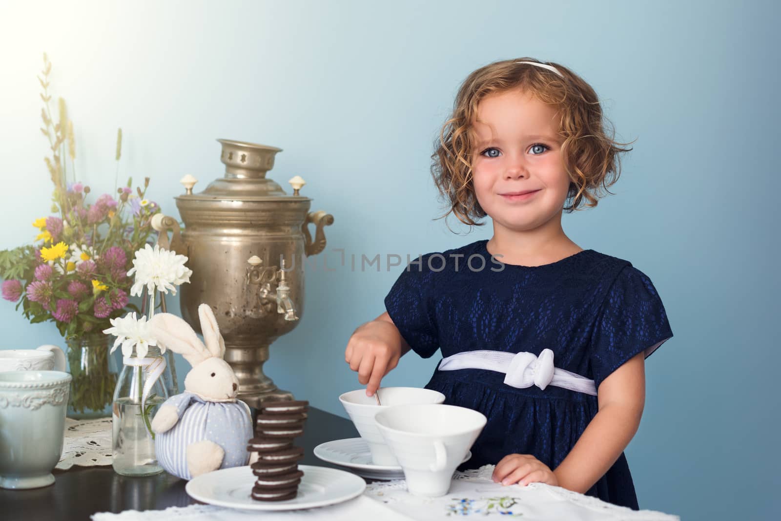 Adorable toddler girl  playing tea party with toy dishess in sunny room