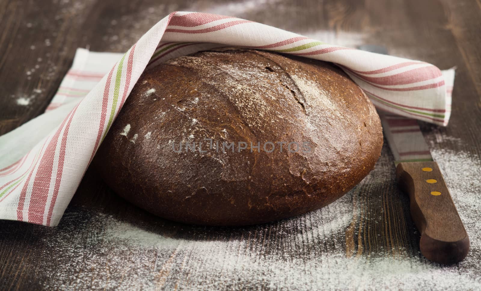 Rye bread under a towel on wooden table