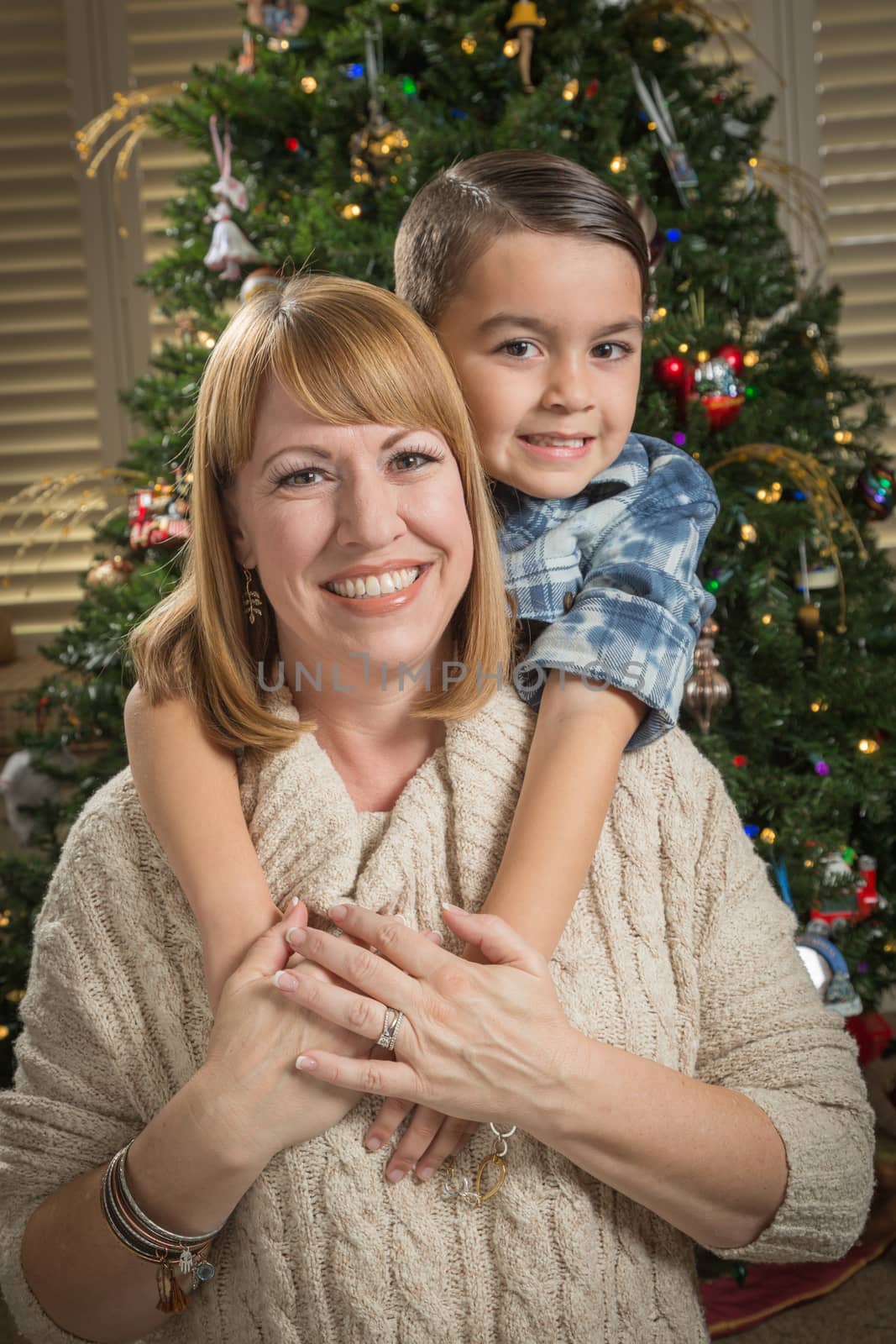 Mother and Mixed Race Son Hug Near Christmas Tree by Feverpitched