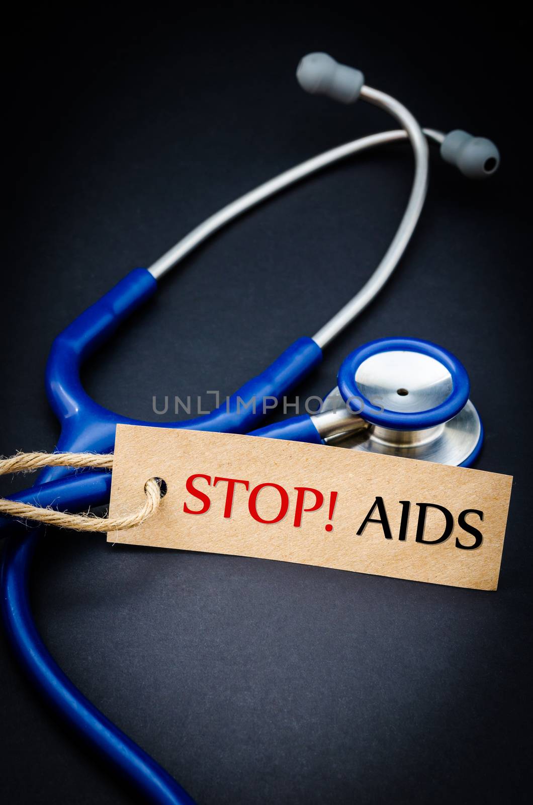 Stop AIDS in paper tag with stethoscope on black background - health concept. Medical conceptual