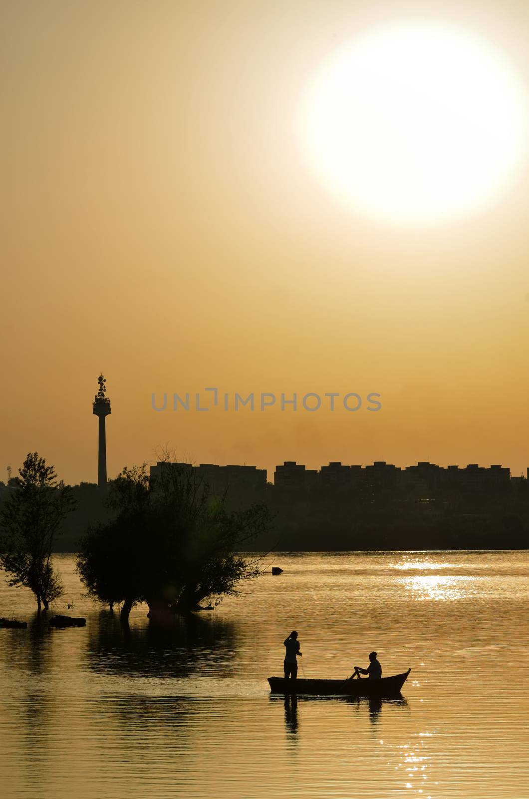 silhouette of fishermen with and orange sun on Danube river