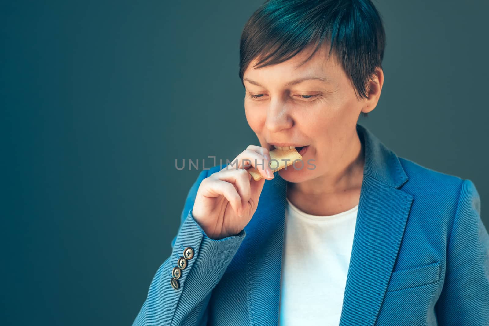 Businesswoman eating cookie on a break by stevanovicigor