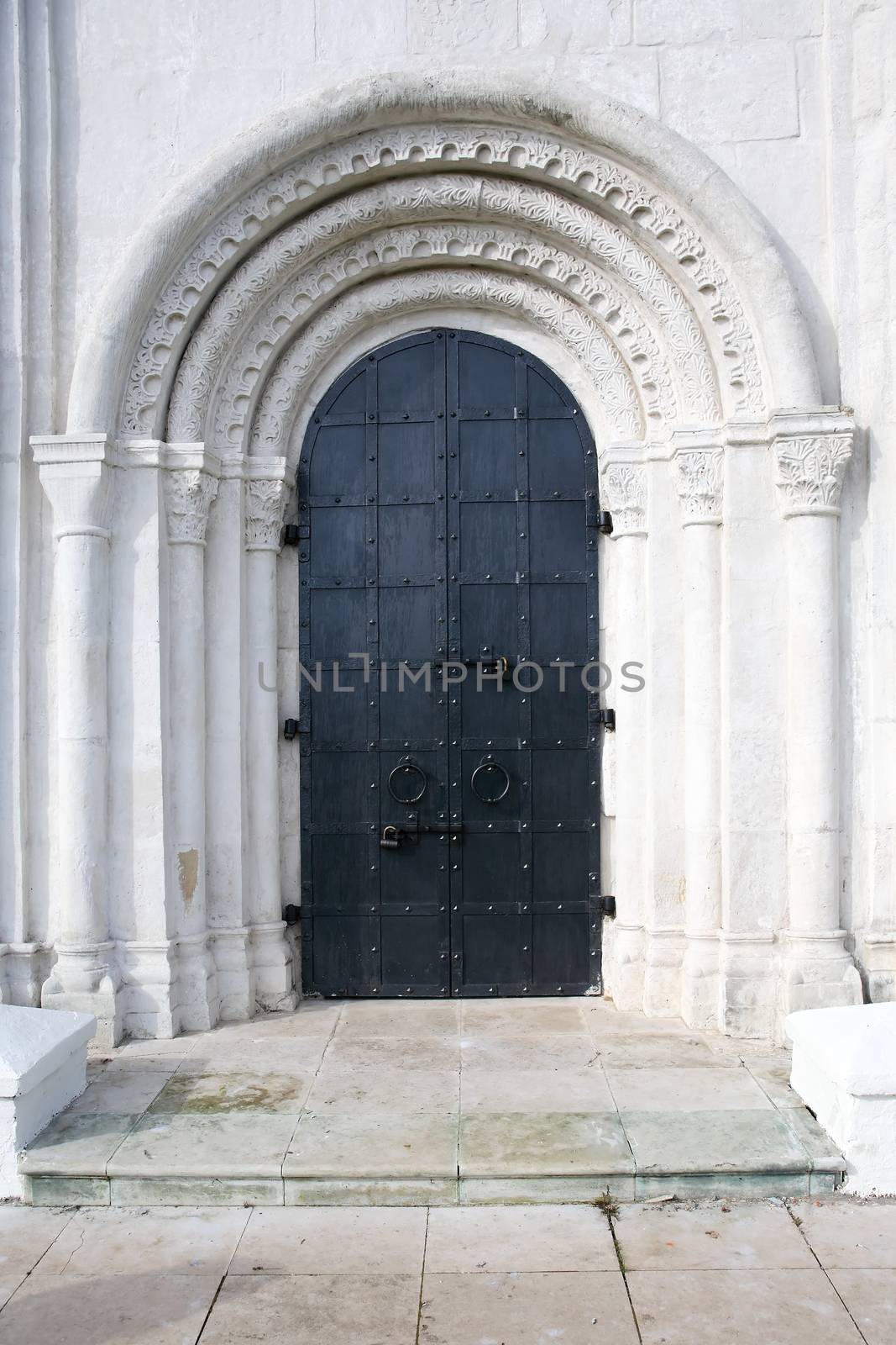 Old Russian church entrance. Arch in wall with big black metal door