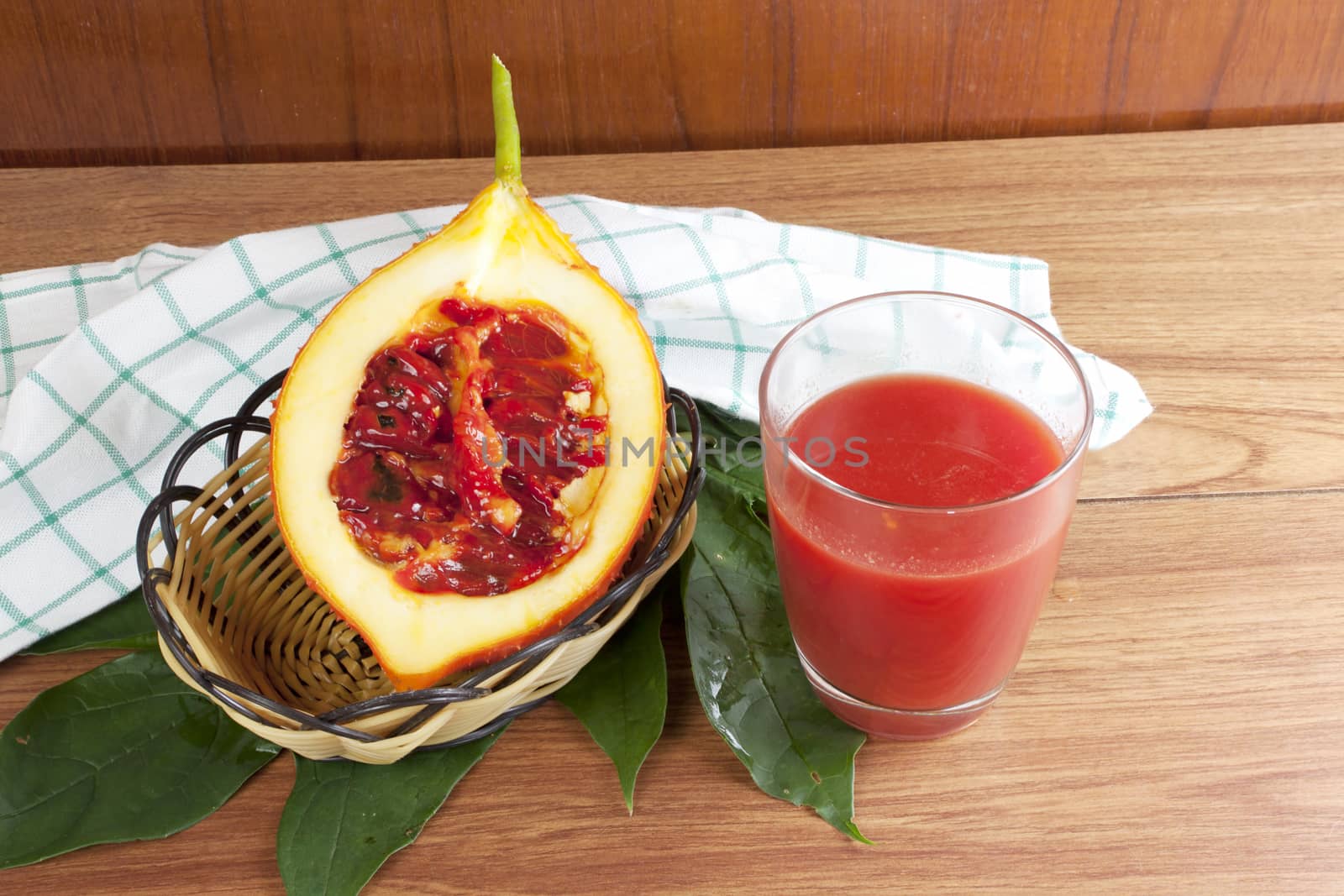 Baby Jack fruit and juice (Or Cochinchin Gourd, Spiny Bitter Gourd, Sweet Gourd, Momordica cochinchinensis, Momordica cochinchinensis (Lour) Spreng.) on wood table