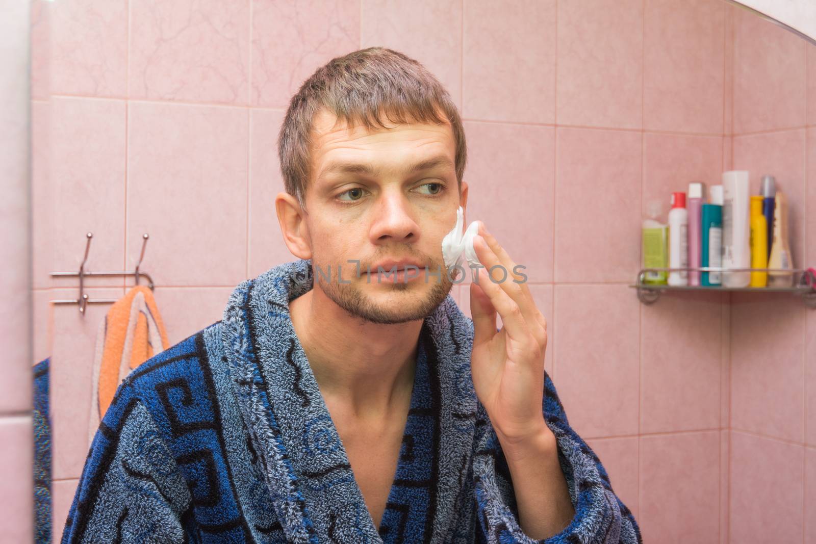 The young man begins to apply shaving foam on face
