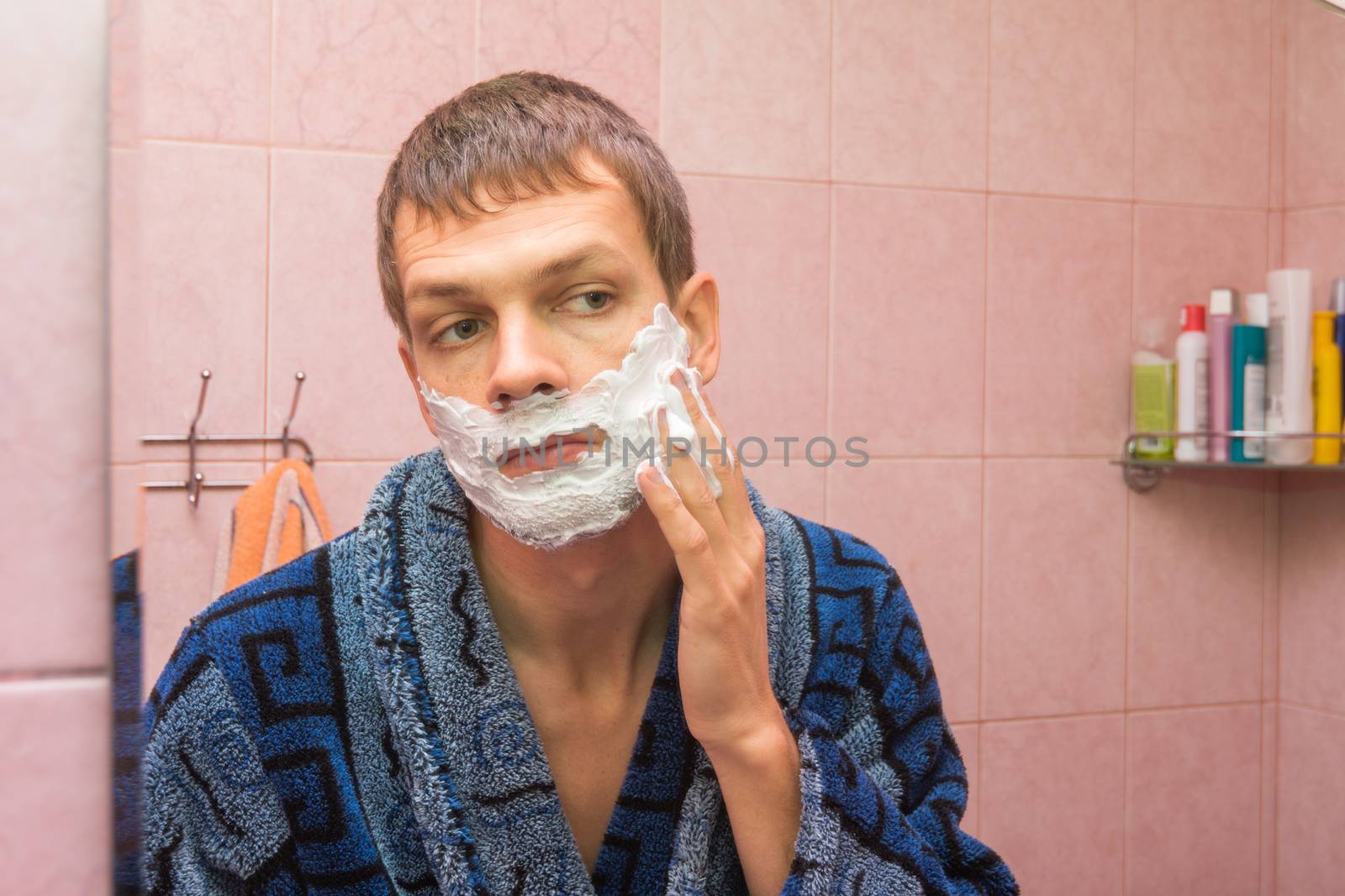 The young man gets shaving foam on face