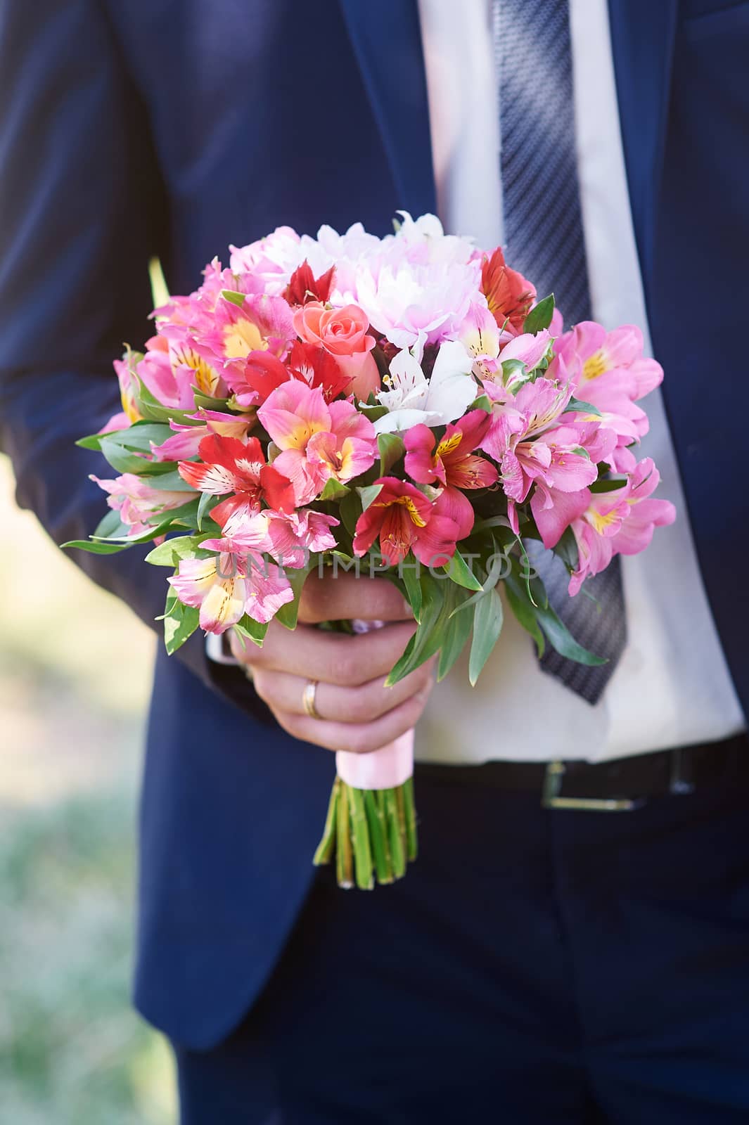 groom holds the brides bouquet in wedding day by timonko