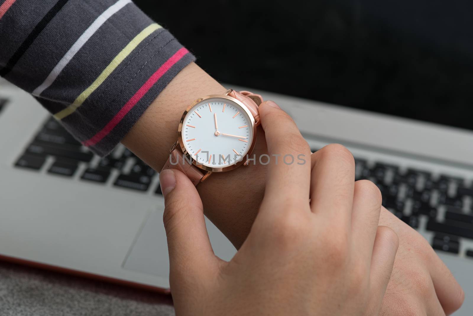 Girl's hand with wrist watch in front of notebook computer
