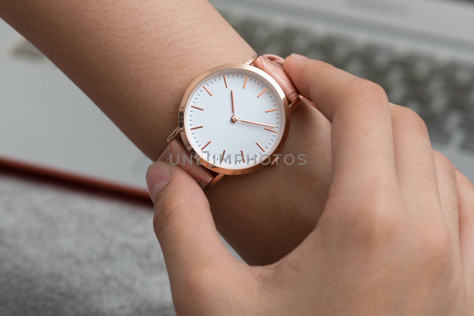 Wrist watch on girl's hand in front of a laptop computer