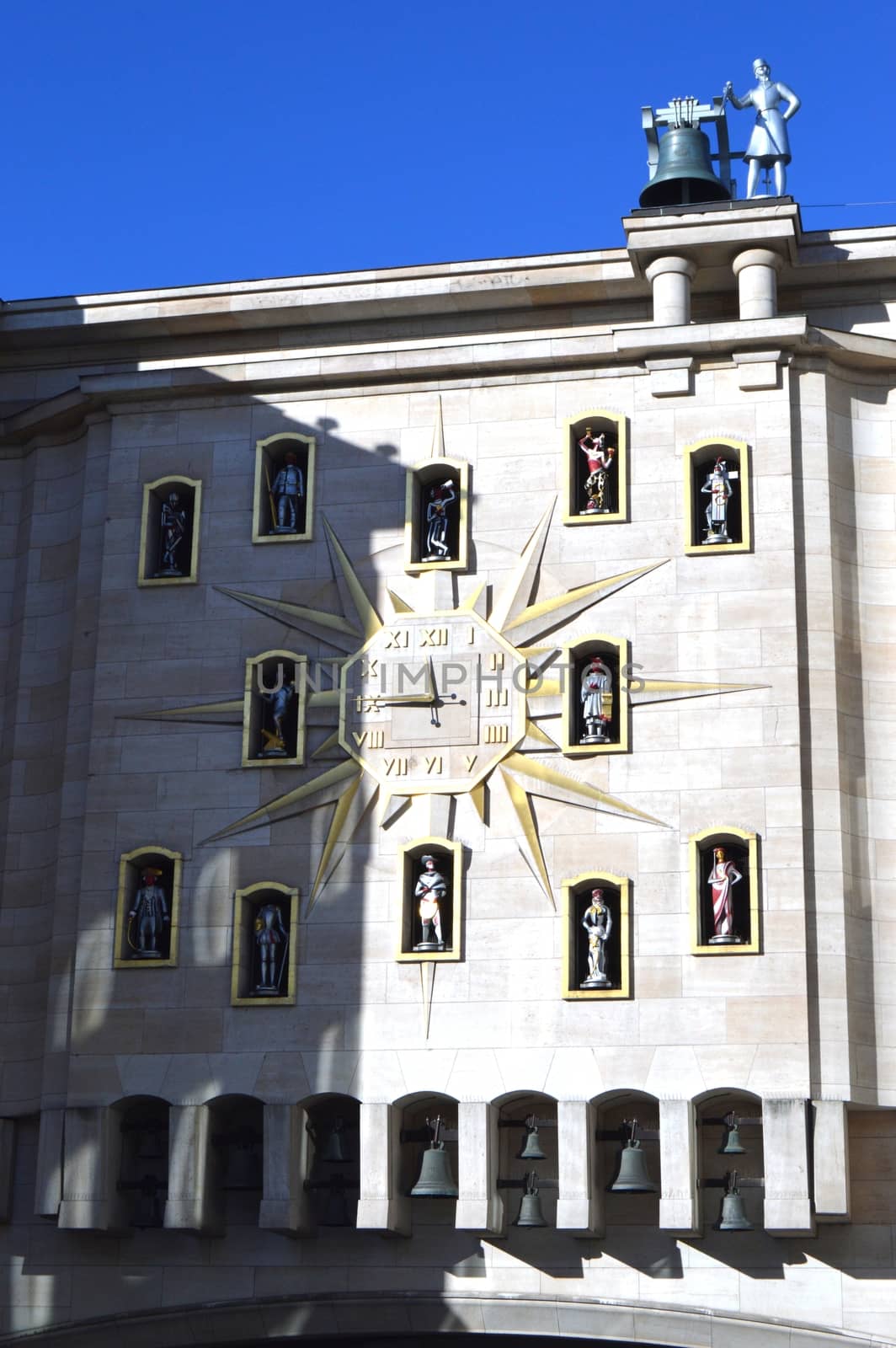 Clock face on a sun-shaped facade with figurines and a bell ringer