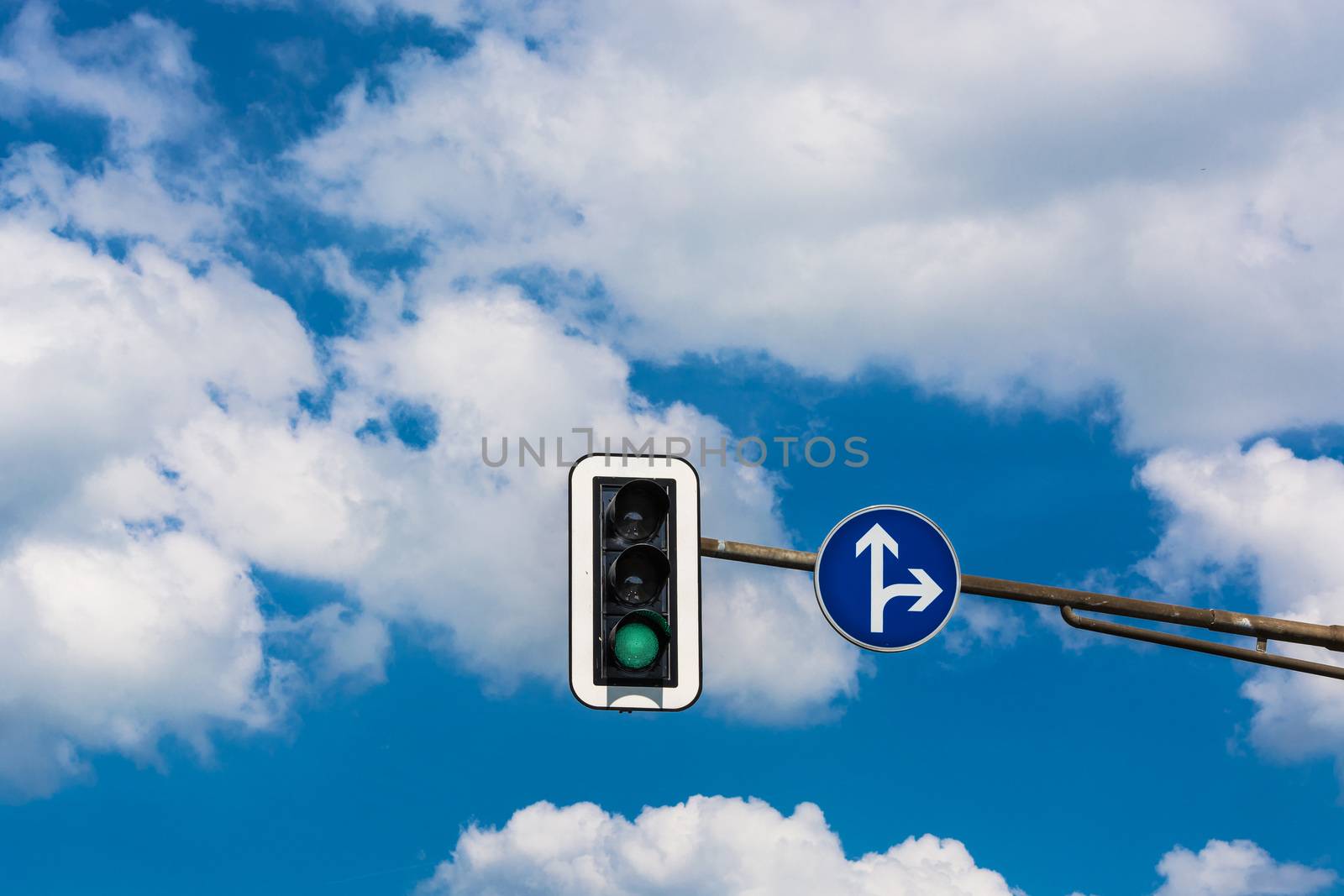 Traffic light and road sign attached to a pole on the street.