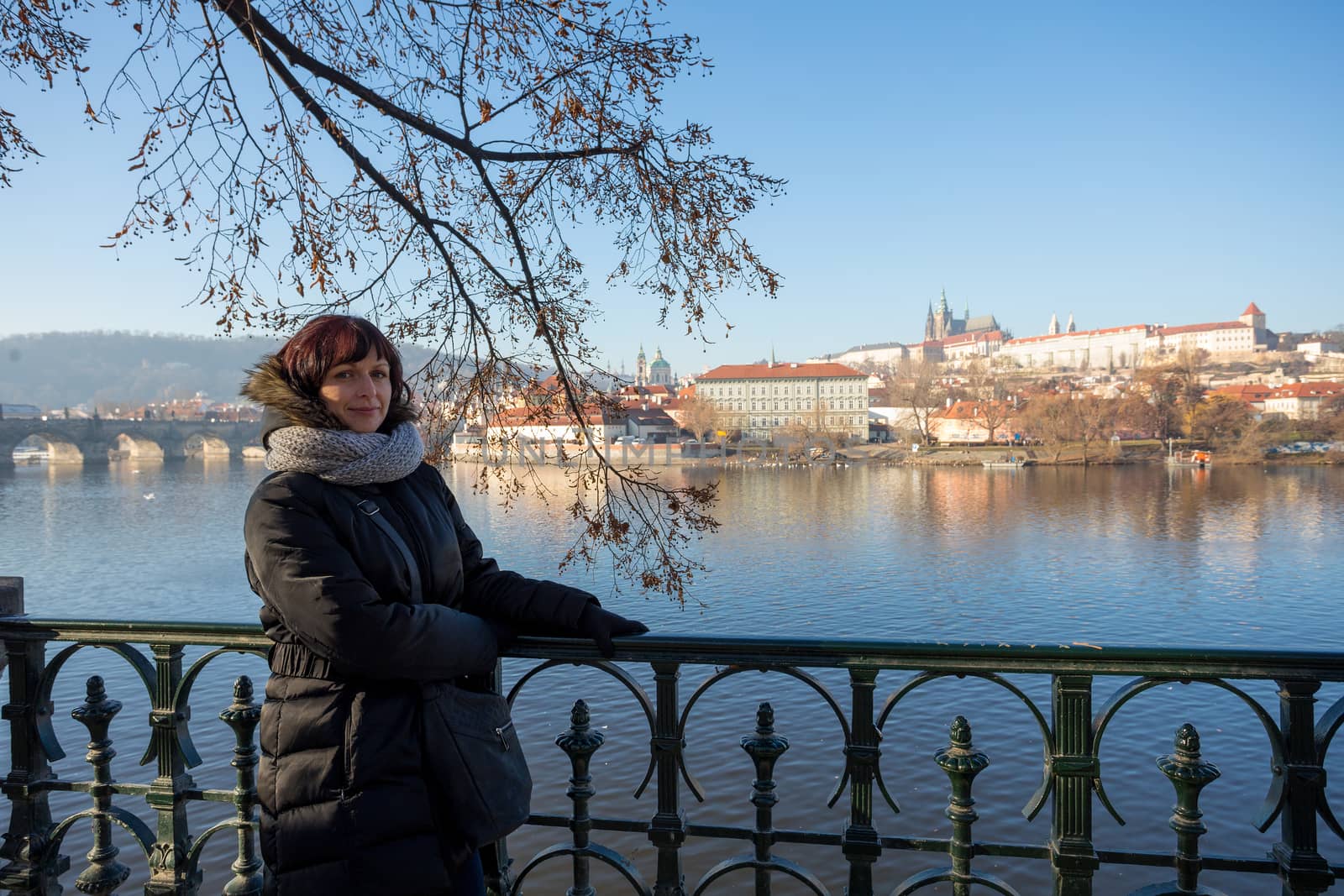 Beautiful Woman in Prague embankment on river Vltava, in background st Vitus cathedral and prague Castle