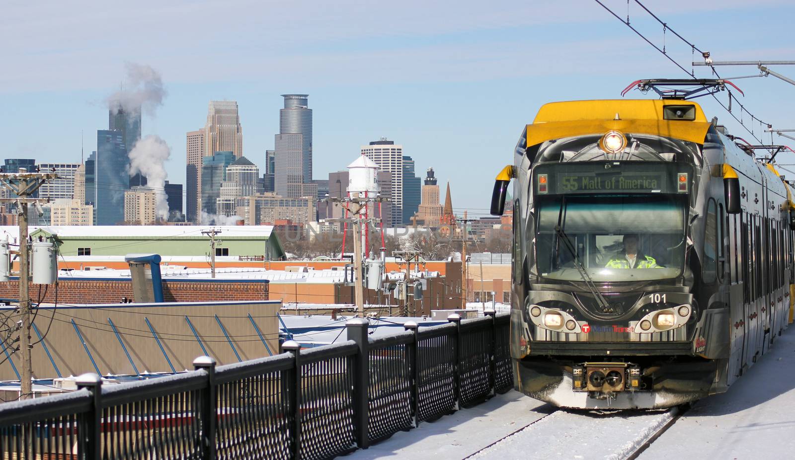 A light rail train passing by the skyline of downtown Minneapolis, Minnesota.