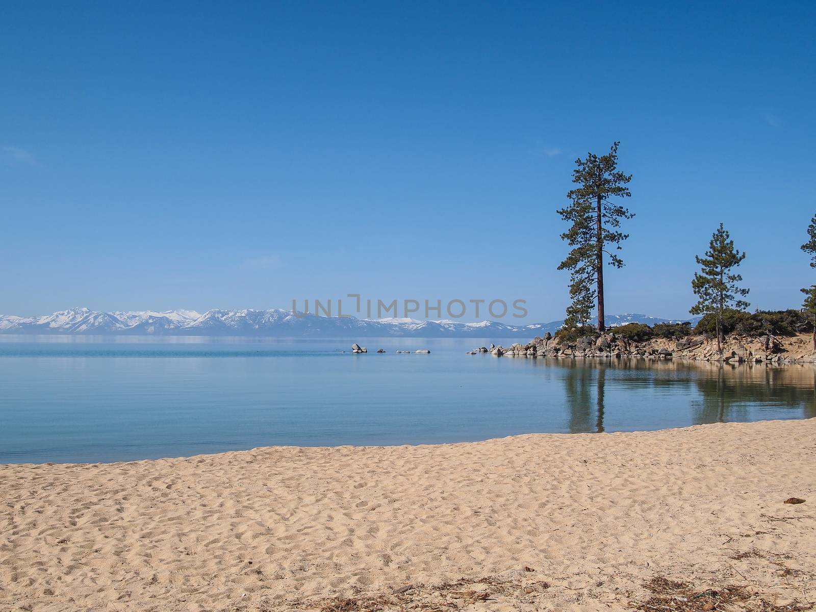 Scenic view of beautiful Lake Tahoe in Spring, landscape of the United States of America, clear water, nice sky, stone island, tree, fresh air and snow mountains